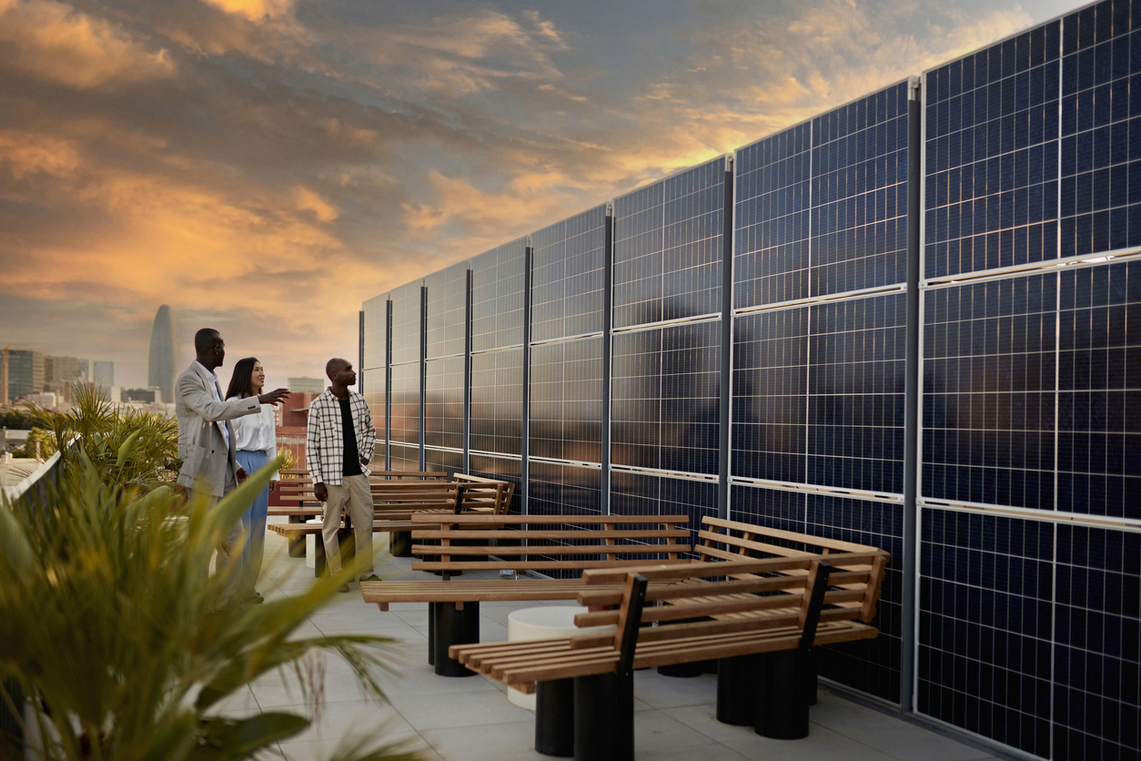 People standing on a rooftop with solar panels and plants